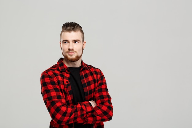 Jeune bel homme posant sur un mur gris.