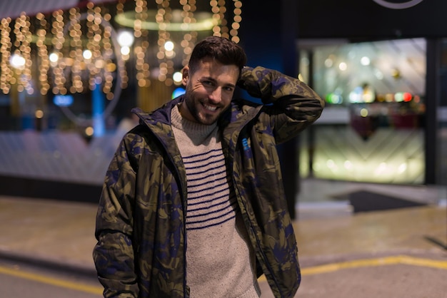 Jeune bel homme possing et souriant Street style la nuit