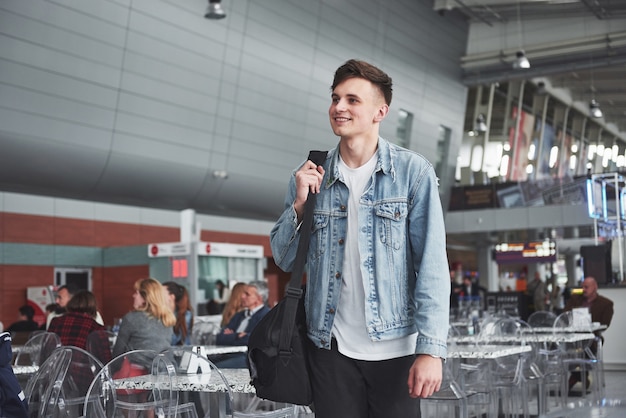 Photo gratuite jeune bel homme avec un sac sur son épaule pressé de l'aéroport.