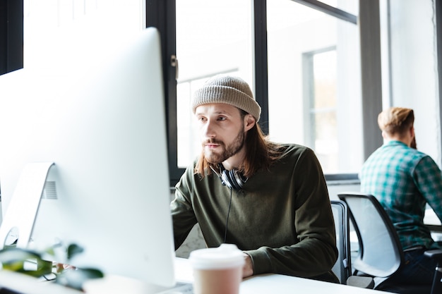 Photo gratuite jeune bel homme travaille au bureau à l'aide d'ordinateur