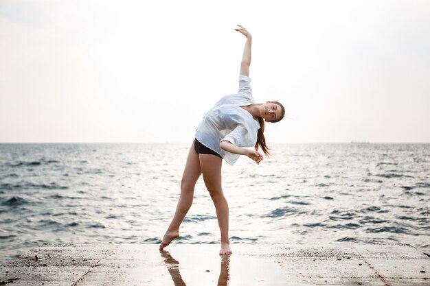 Jeune belle ballerine dansant et posant à l'extérieur, digue