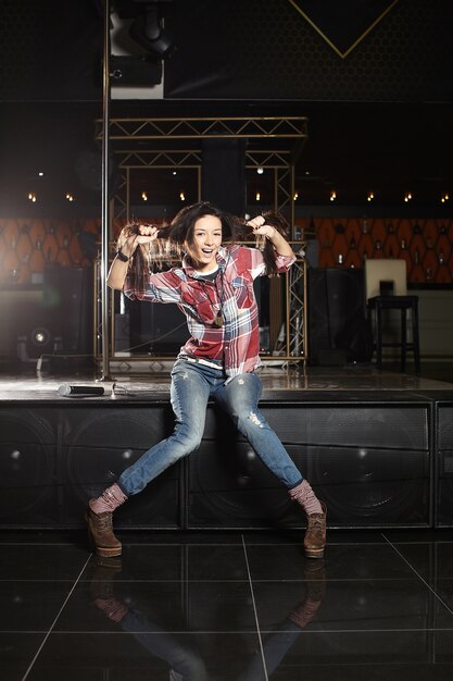 jeune belle chanteuse pop star drôle avec microphone assis sur la scène dans le club