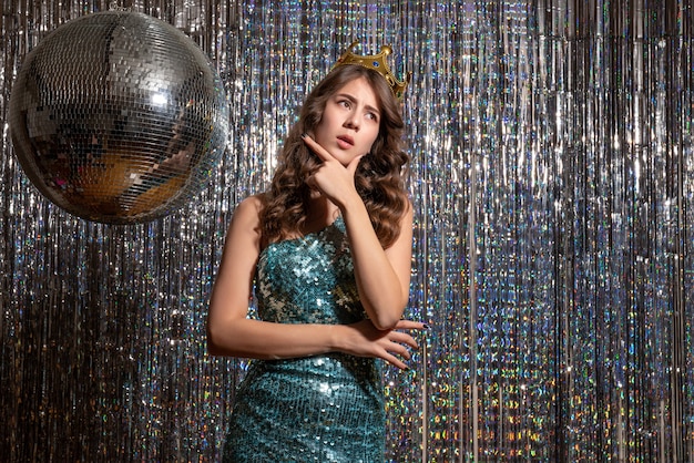 Jeune Belle Dame Réfléchie Vêtue D'une Robe Brillante Bleu Vert Avec Des Paillettes Avec Couronne Dans La Partie