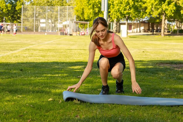 Jeune belle dame tenant son tapis de sport et le regardant