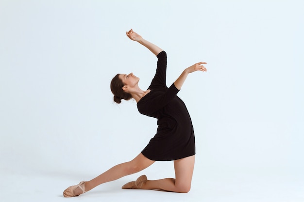 Jeune belle danseuse contemporaine posant sur mur blanc. Copiez l'espace.