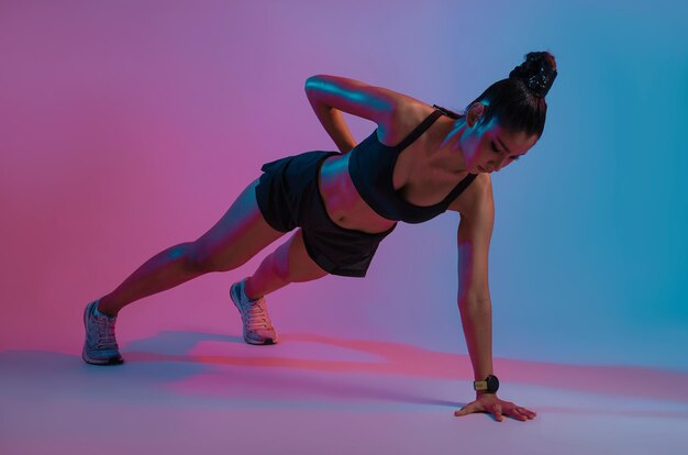 Jeune belle femme asiatique avec un corps athlétique faisant des pompes au centre de fitness moderne