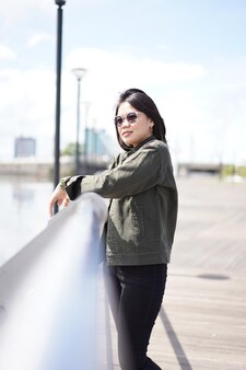 Jeune belle femme asiatique portant une veste et un jean noir posant à l'extérieur