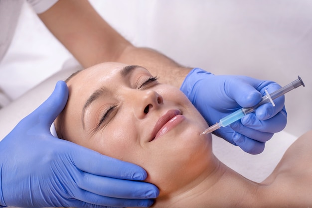 Jeune belle femme caucasienne pendant le traitement à l'acide hyaluronique dans une clinique de beauté