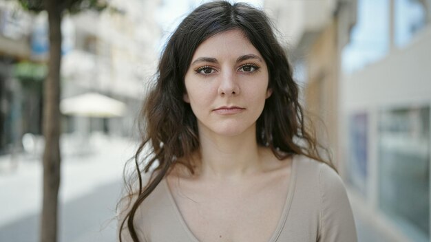 Jeune belle femme hispanique debout avec une expression sérieuse dans la rue