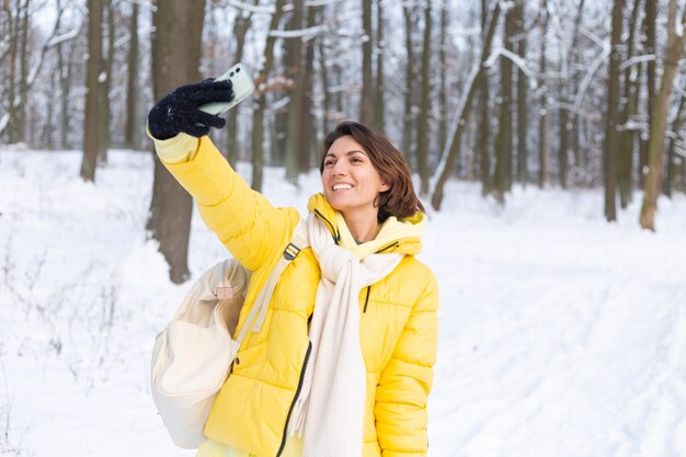 Jeune belle femme joyeuse heureuse dans le blog vidéo de la forêt d'hiver, fait une photo de selfie