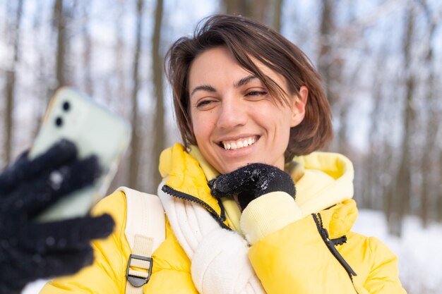 Jeune belle femme joyeuse heureuse dans le blog vidéo de la forêt d'hiver, fait une photo de selfie