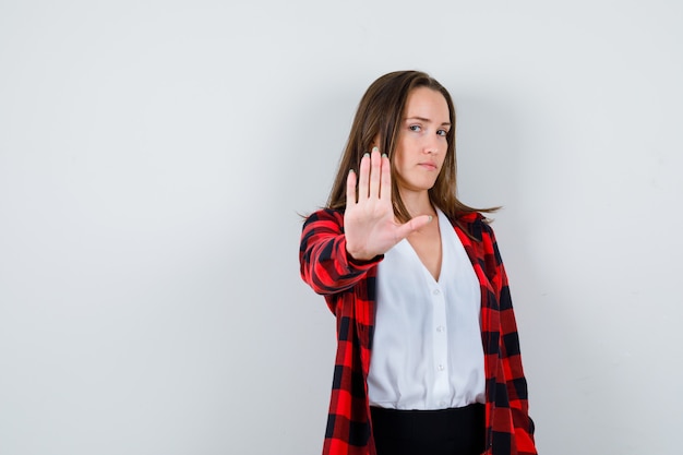 Jeune belle femme montrant un geste d'arrêt en tenue décontractée et semblant stricte. vue de face.