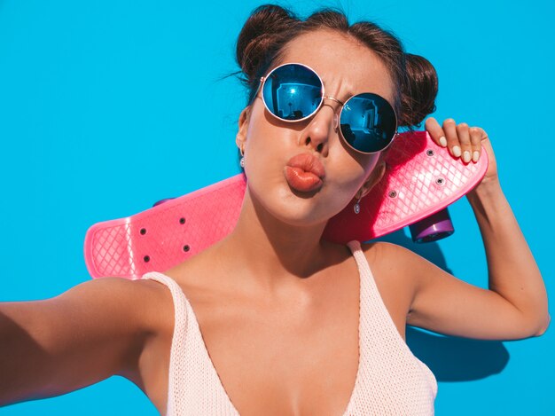 Jeune belle femme sexy hipster souriante à lunettes de soleil.