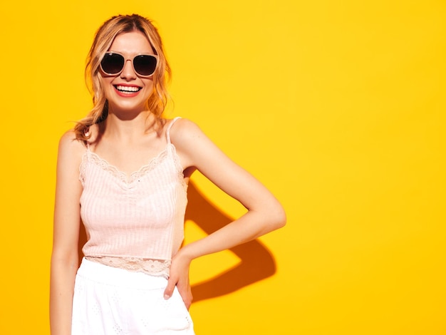 Jeune belle femme souriante dans des vêtements d'été à la mode Sexy femme insouciante posant près de bleu jaune en studio Modèle positif s'amusant Gai et heureux En lunettes de soleil