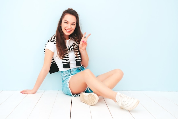 Jeune belle femme souriante dans des vêtements hipster d'été à la mode