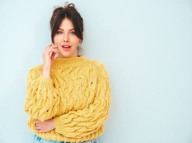 Jeune belle femme souriante en jean et pull hipster jaune d'été à la mode