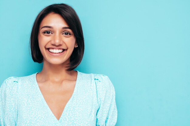 Jeune belle femme souriante en robe blanche d'été à la mode Sexy femme insouciante posant près du mur bleu en studio Modèle positif s'amusant Gai et heureux Isolé