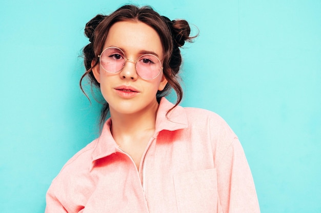 Jeune belle femme souriante en salopette rose d'été à la mode Sexy femme insouciante posant près du mur bleu en studio avec deux cornes Modèle positif s'amusant et devenant fou Enthousiaste et heureux