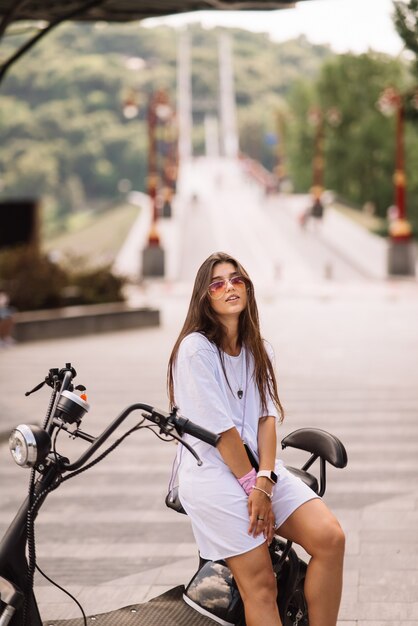 Jeune belle femme et un transport écologique de scooter électrique