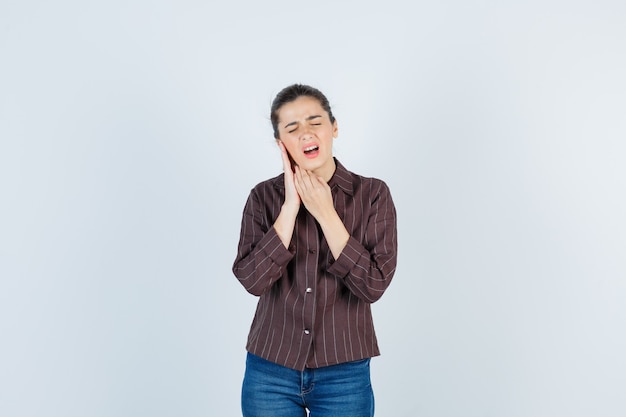 Jeune belle femme en veste avec la main sur l'oreille et à la vue de face douloureuse.