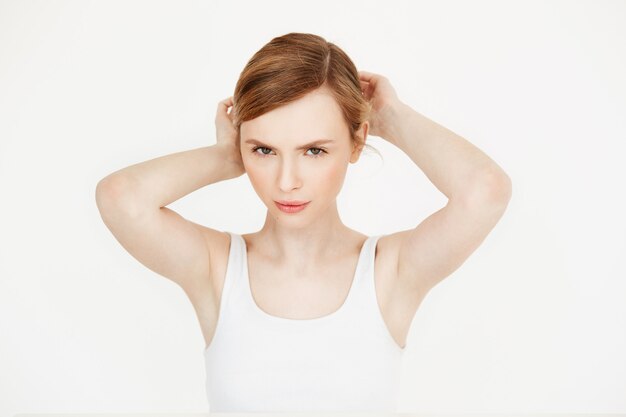 Jeune belle fille blonde avec une peau douce et propre, assis à table, corrigeant la coiffure. Beauté et spa.