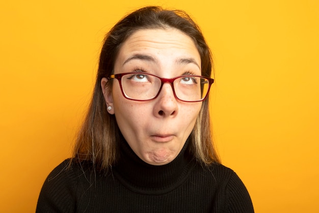 Jeune belle fille dans un col roulé noir et des lunettes à la perplexité