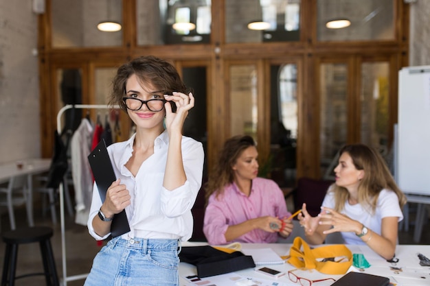 Photo gratuite jeune belle fille à lunettes et chemise blanche regarde rêveusement