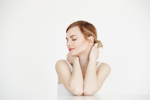 Jeune belle fille avec une peau parfaitement propre, souriant avec les yeux fermés, assis à table. Spa de beauté et cosmétologie.