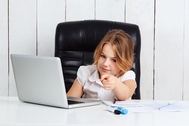 Jeune belle fille pointant le doigt vers la caméra au bureau.