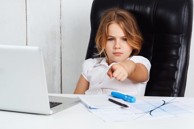 Jeune belle fille pointant le doigt vers la caméra au bureau.