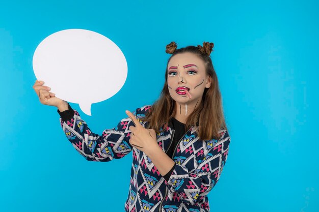 Jeune belle fille portant un maquillage créatif et pointant du doigt le tableau d'idées. Photo de haute qualité