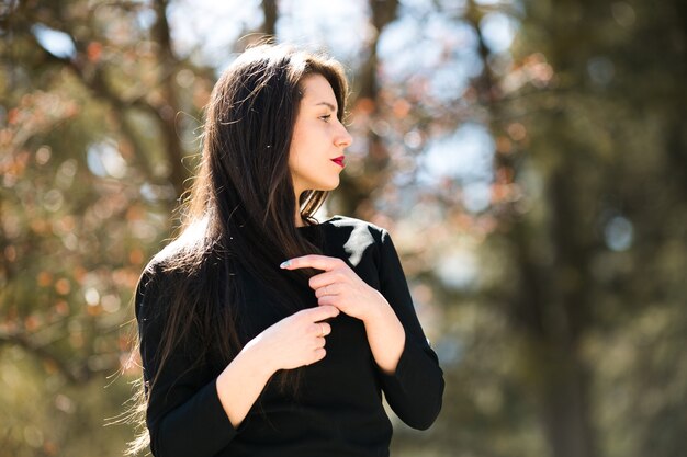 Jeune belle fille posant dans une veste en cuir noire en parc