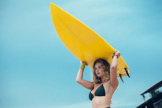 jeune belle fille posant sur la plage avec une planche de surf, surfeuse, vagues de l&#39;océan
