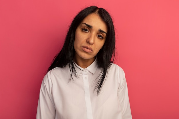 Jeune belle fille regardant droit devant portant un t-shirt blanc isolé sur rose avec espace copie