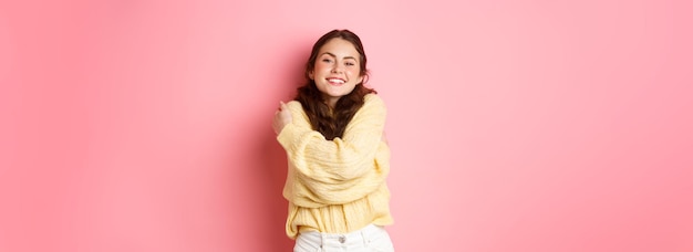 Photo gratuite jeune belle fille se sentant en bonne santé et heureuse se serrant dans ses bras tout en portant un pull doux souriant pl