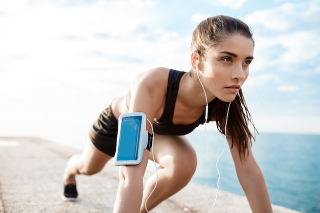 Jeune belle fille sportive se prépare à courir au bord de mer.