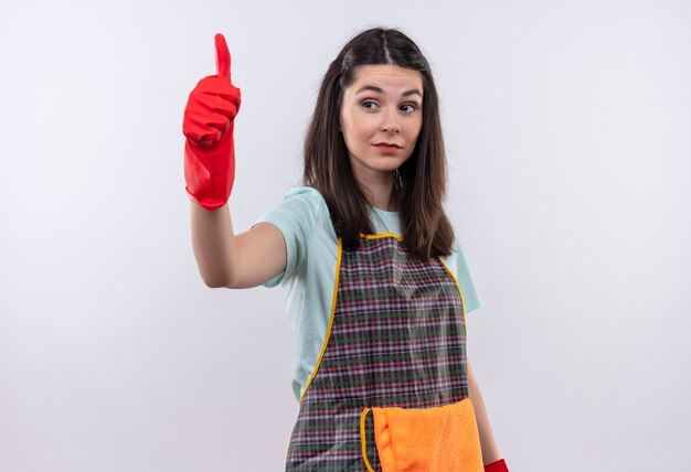 Jeune belle fille en tablier et gants en caoutchouc à la confiance en montrant les pouces vers le haut