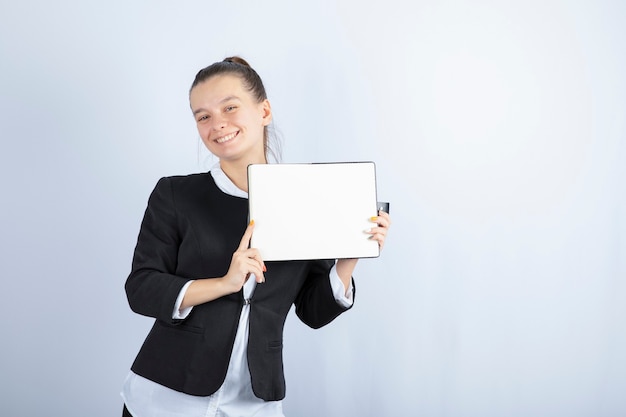 Jeune belle fille tenant un livre en souriant sur fond blanc. Photo de haute qualité