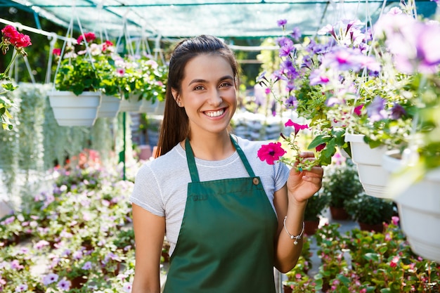 Jeune belle fleuriste posant, souriant parmi les fleurs.