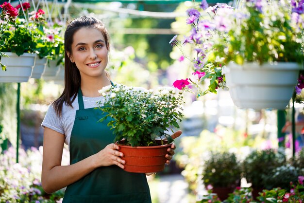 Jeune belle fleuriste posant, souriant parmi les fleurs.