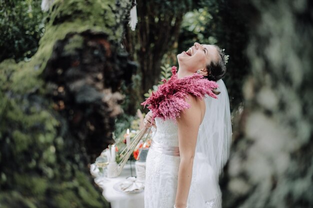 Jeune belle mariée tenant un bouquet dans un style bohème