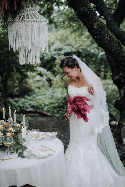 Jeune belle mariée tenant un bouquet dans un style bohème