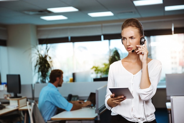 Jeune belle opérateur téléphonique de soutien féminin parlant, consultant, sur le bureau