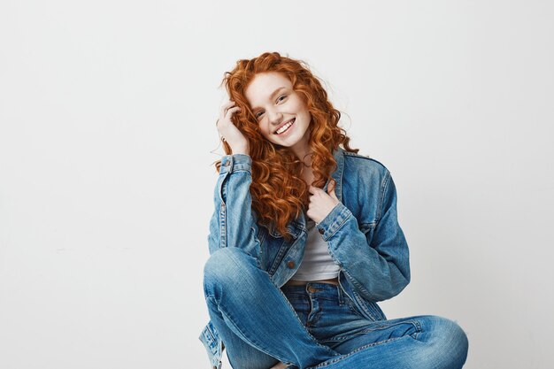 Jeune belle rousse souriante assise sur une boîte. Copiez l'espace.