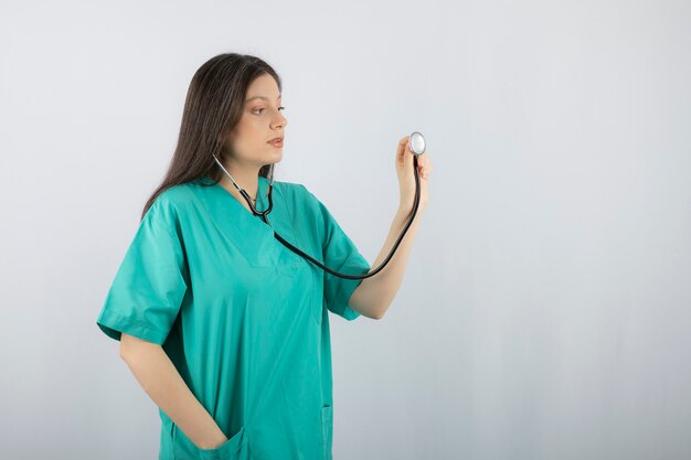 Jeune belle travailleuse médicale prête à vérifier le patient avec un stéthoscope.