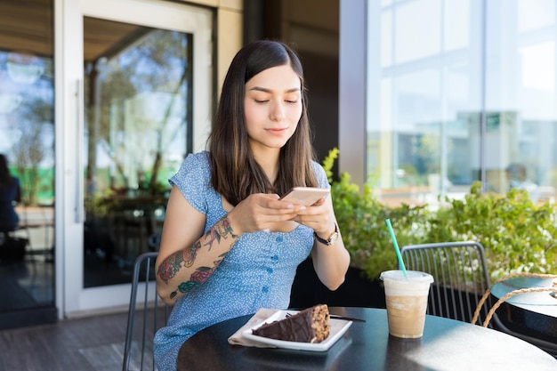 Jeune blogueur photographiant des pâtisseries via un smartphone dans un centre commercial