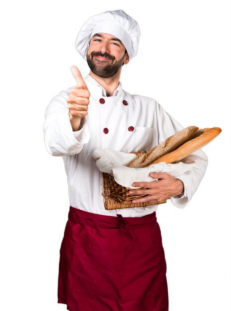 Jeune boulanger tenant du pain et avec le pouce vers le haut