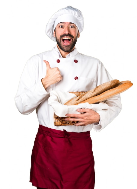 Jeune boulanger tenant du pain et avec le pouce vers le haut