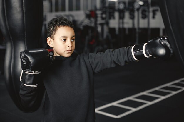 Jeune boxeur travailleur apprenant à boxer. Enfant au centre sportif. Enfant prenant un nouveau passe-temps