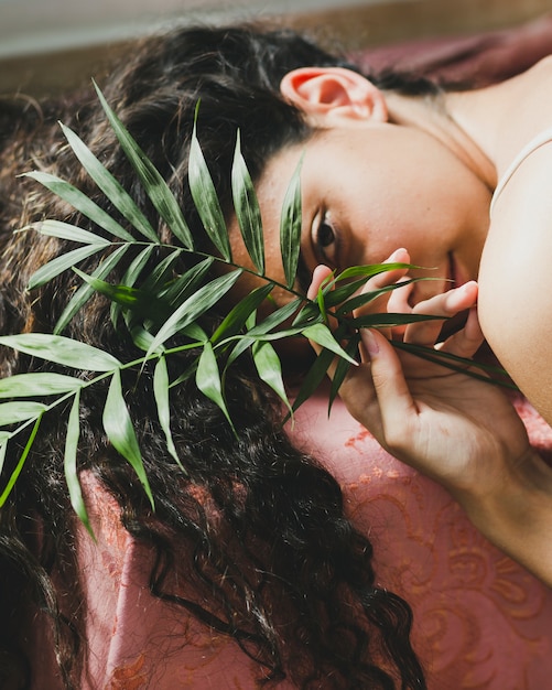 Jeune brune avec des feuilles en regardant la caméra